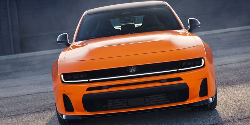 Front view of an orange Dodge Charger Daytona SRT EV concept car on asphalt.