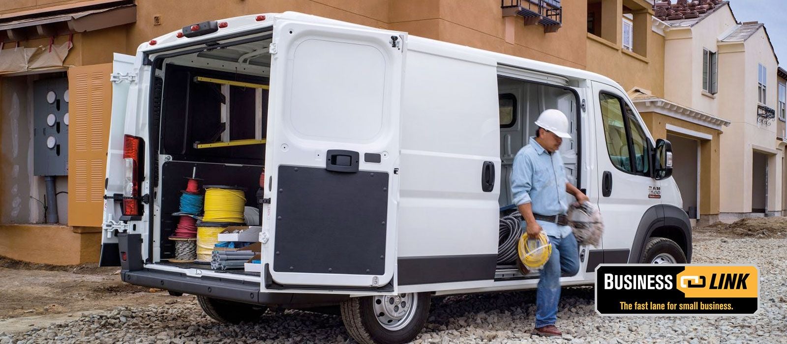 A white cargo van with an open side door and rear, revealing tools and spools of wire
